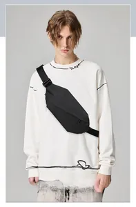 Detailed view of black minimalist oxford chest bag worn over a white graphic sweatshirt