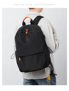 Rear view of a black nylon backpack with orange details on a male model for scale