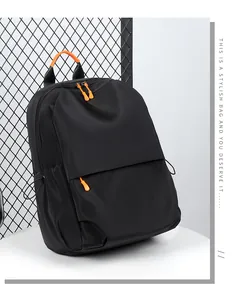 Detail of waterproof black backpack featuring orange contrast zippers and side drawstring