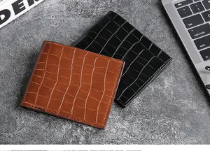 Detail shot of black and brown crocodile embossed bifold wallets on a modern office desk