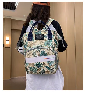 Tropical leaf print diaper backpack with reflective safety strip shown on model