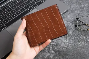 Detail of hand holding a brown crocodile embossed leather bifold wallet for men