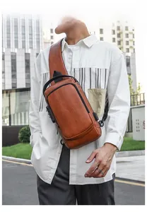 Detailed view of a brown vintage leather chest bag with a USB port on a male model
