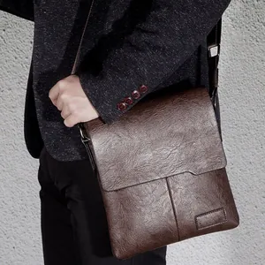 Men's vintage brown leather crossbody bag shown on a model in a charcoal textured suit