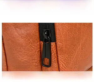Detail of glossy black metal zipper on textured brown leather bag with stitching