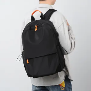 Minimalist black laptop backpack with orange accents shown on a male model back