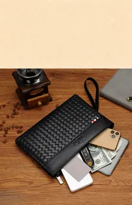 Detail of woven texture clutch bag with phone and essentials on wooden background
