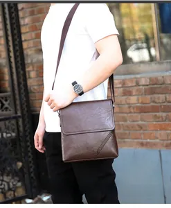 Detail of dark brown leather crossbody bag featuring lychee texture and adjustable strap