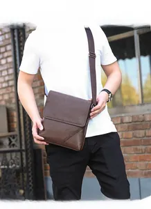 Detail view of brown leather men's messenger bag with diagonal stitching and adjustable strap
