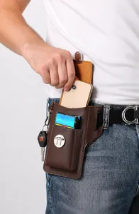 Dettaglio del marsupio in pelle marrone con smartphone, pacchetto di sigarette e chiavi