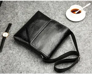 Flat lay of black PU leather men shoulder bag with watch and coffee on grey background