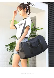Large black travel bag with reinforced straps and shoulder belt shown in street style
