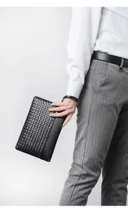 Macro detail of the woven texture and embossed logo on the black men's leather clutch bag