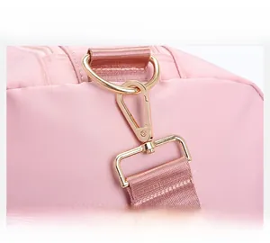Close-up of golden detachable shoulder strap buckle on pink travel bag with woven strap