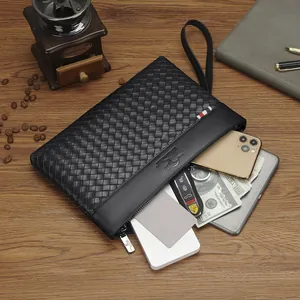 Men's business woven leather clutch bag with large capacity and wrist strap on wooden desk