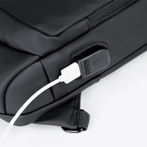 Detail van de geïntegreerde USB-oplaadpoort op de zwarte crossbodytas met kabel