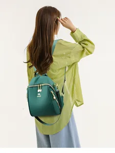 Dettaglio dello zaino in nylon verde scuro con logo a canguro dorato e doppie cerniere lampo