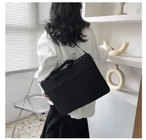 Vista posteriore di una borsa per laptop nera con manici e tracolla indossata da un modello