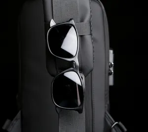 Detail of black sunglasses hanging on a backpack strap in a low-key outdoor setting