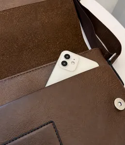 Nahaufnahme der Vordertasche einer braunen PU-Leder Umhängetasche mit Smartphone-Fach