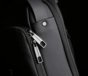 Detail shot of black waterproof nylon sling bag with dual metal zippers and silver rivet