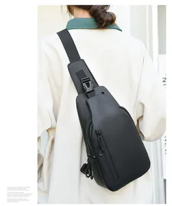Homme portant un sac bandoulière noir imperméable avec plusieurs compartiments zippés