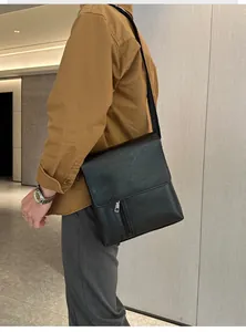 Detail einer schwarzen Umhängetasche aus Leder mit Reißverschlusstasche und Klappe
