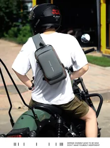 Detail of waterproof crossbody bag with security lock shown on an outdoor motorcycle rider