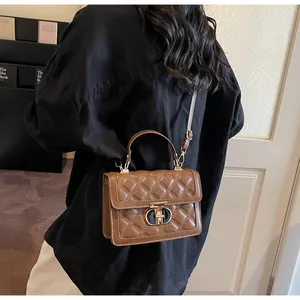 Detailed view of brown quilted leather crossbody bag with golden metal lock on model