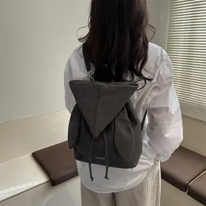 Minimalist dark gray suede backpack with wing design and drawstring closure on model