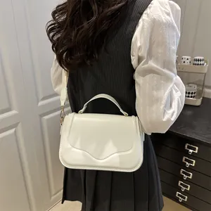 Minimalist white faux leather crossbody bag with top handle and sleek curved flap design