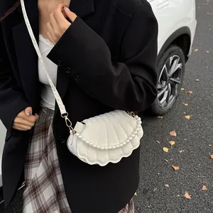 White shell-shaped shoulder bag with quilted texture and decorative pearl chain strap