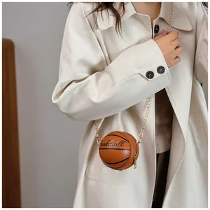 Detail of trendy basketball-shaped crossbody bag with gold chain strap on model