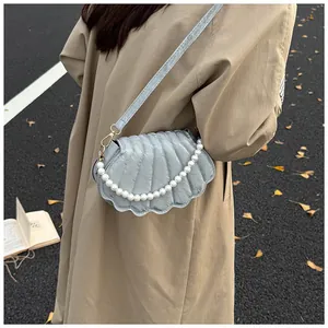 Detail of shell-shaped bag with pleated texture and pearl chain strap on autumn coat