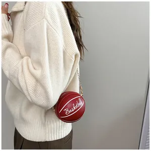 Detail of red basketball-shaped crossbody bag with gold chain and white lettering