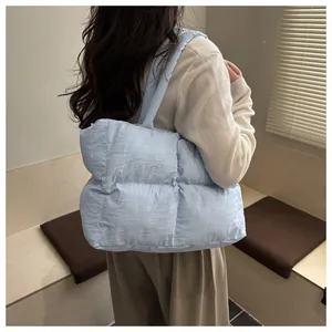 Dettaglio della borsa tote trapuntata celeste indossata da una modella in interni accoglienti