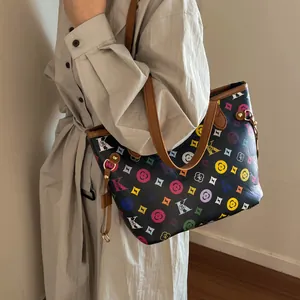 Detail of printed tote bag featuring colorful monogram pattern and brown leather straps