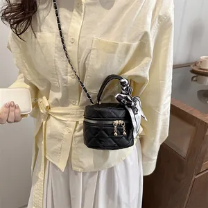 Quilted black leather bucket bag with chain strap and decorative bow scarf on model