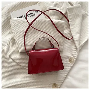 Dettaglio mini borsa rossa in pelle verniciata lucida con patta strutturata e tracolla