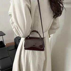Borsa a tracolla quadrata in vernice marrone scuro con patta a onde e design elegante