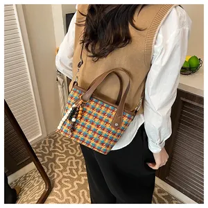 Dettaglio della borsa tote vintage a quadri con trama intrecciata e portachiavi di perline