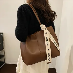 Brown leather large tote bag with decorative fashion ribbon on shoulder, stylish commute style