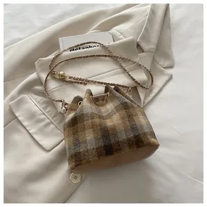 Detail of checkered bucket bag featuring wool fabric, leather base and chain strap