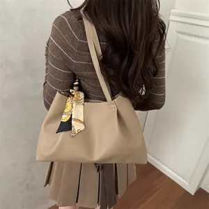Sac fourre-tout en cuir kaki minimaliste avec foulard décoratif porté par un mannequin