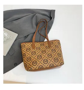 Détails du motif monogramme et des coutures en cuir marron sur le grand sac cabas