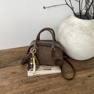 Dettaglio borsa vintage in pelle marrone con pendente di perline e finiture dorate