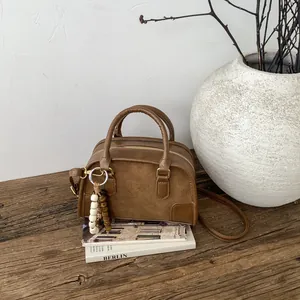 Dettaglio della borsa vintage in pelle marrone su libri con ciondolo in legno decorato