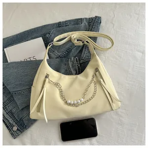 Détail du sac crème avec chaîne de perles argentées et pompons en cuir élégants