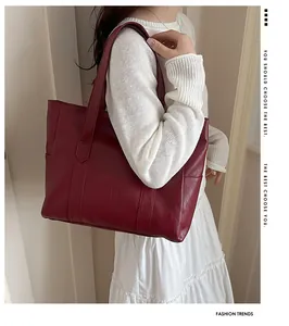 Model trägt eine große burgunderrote Kunstleder-Einkaufstasche mit minimalistischem Design