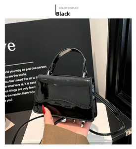 Détail du mini sac en cuir verni noir avec rabat ondulé et finition brillante chic